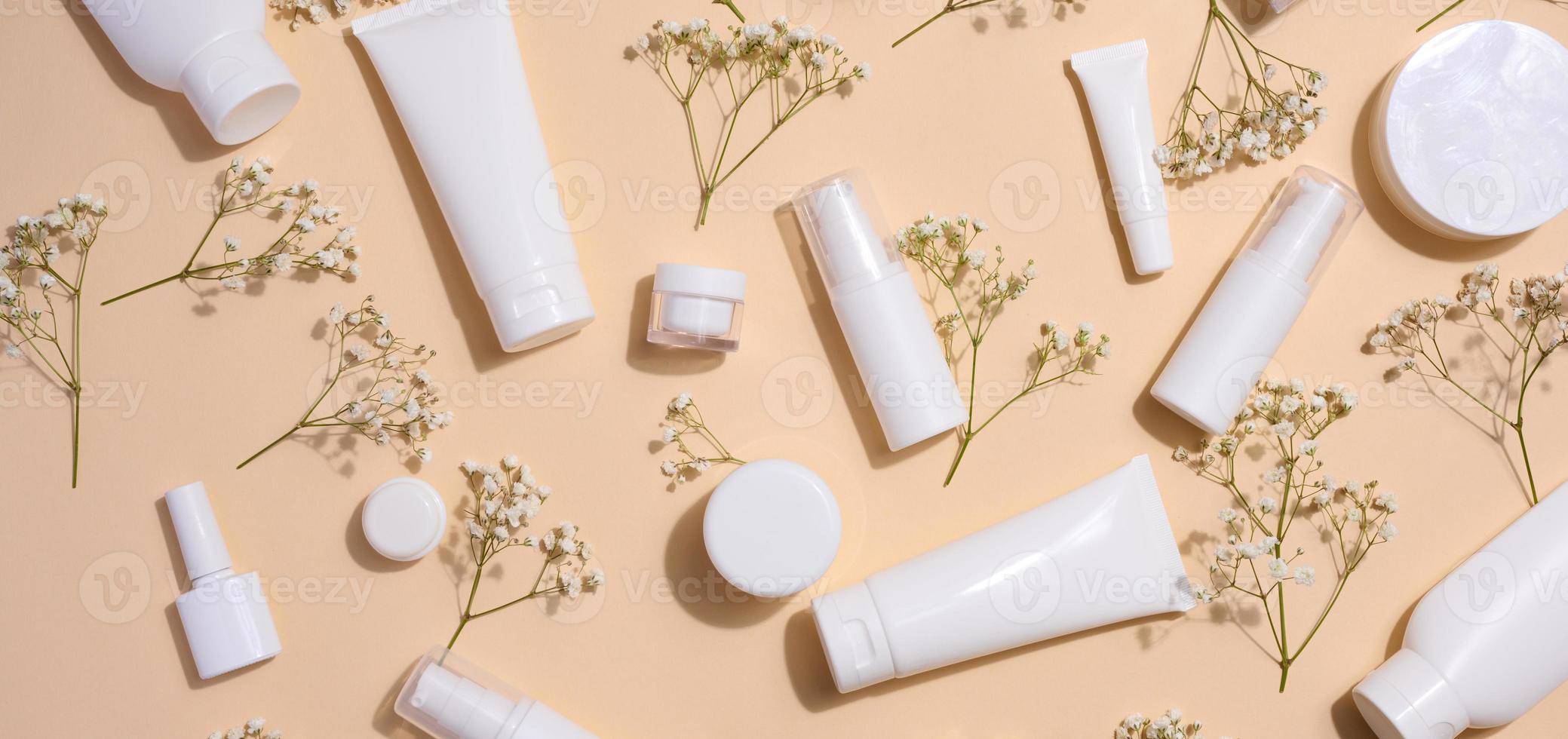 blanco el plastico tubos, frascos, y Gypsophila ramas en un beige fondo, contenedores para cosmético cremas y geles, publicidad y marca promoción, parte superior ver foto