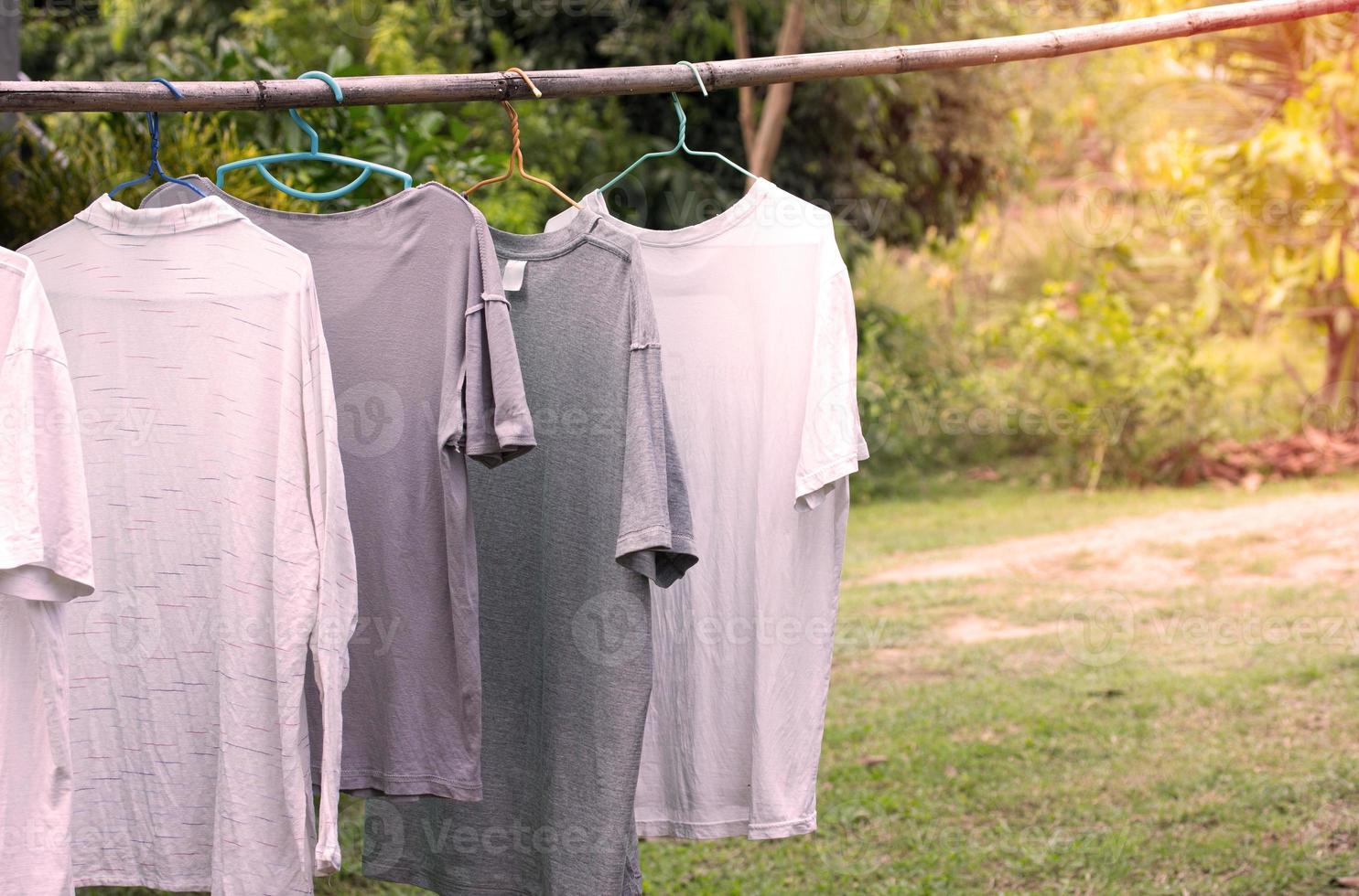 camisetas colgando en de madera bar para seco después limpieza ropa en el jardín al aire libre a país casa foto
