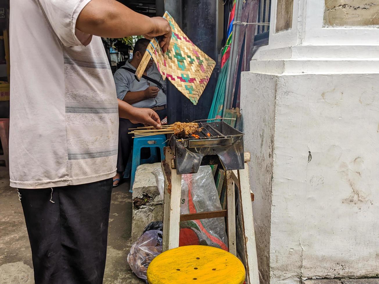 a satay seller roasting satay or sate over a fire photo