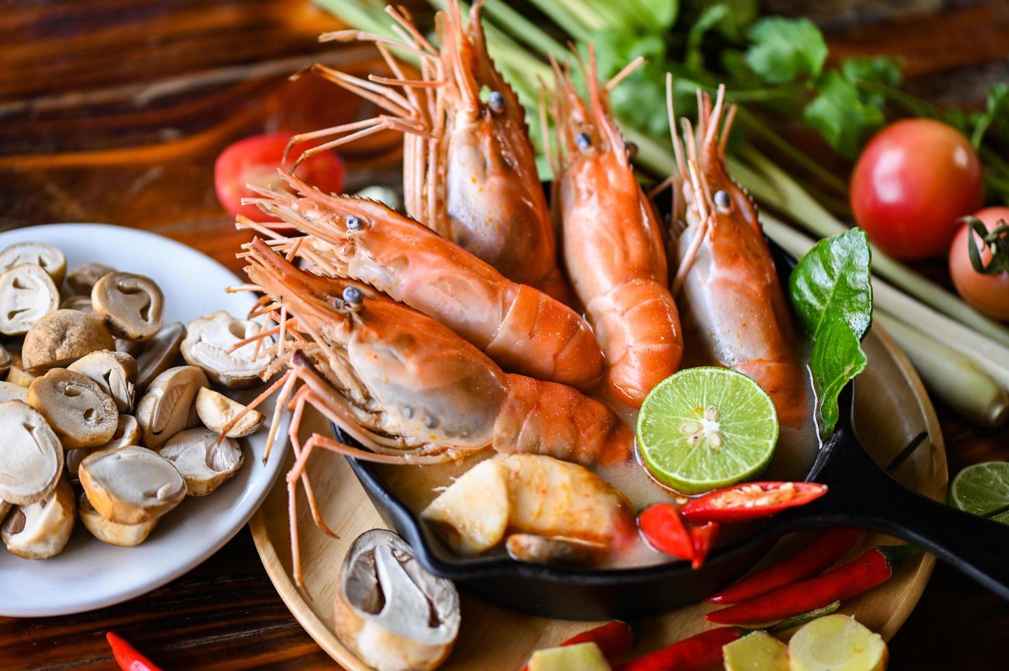 Thai Food Tom Yum Kung, Hot and sour spicy shrimps prawns soup  curry lemon lime galangal red chili straw mushroom on table food, Shrimp soup on seafood soup bowl with thai herb and spices photo