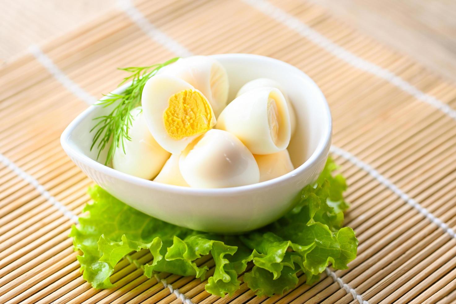 boiled eggs food, quail eggs on white bowl, breakfast eggs with fresh quail eggs and vegetable lettuce on table background photo