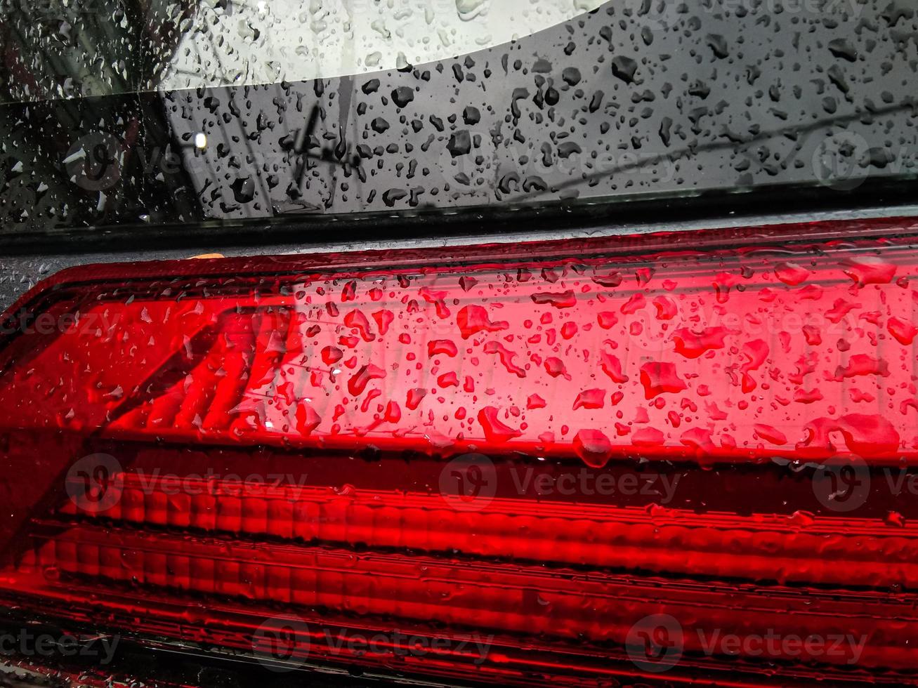 A red tail light with water droplets on it. photo