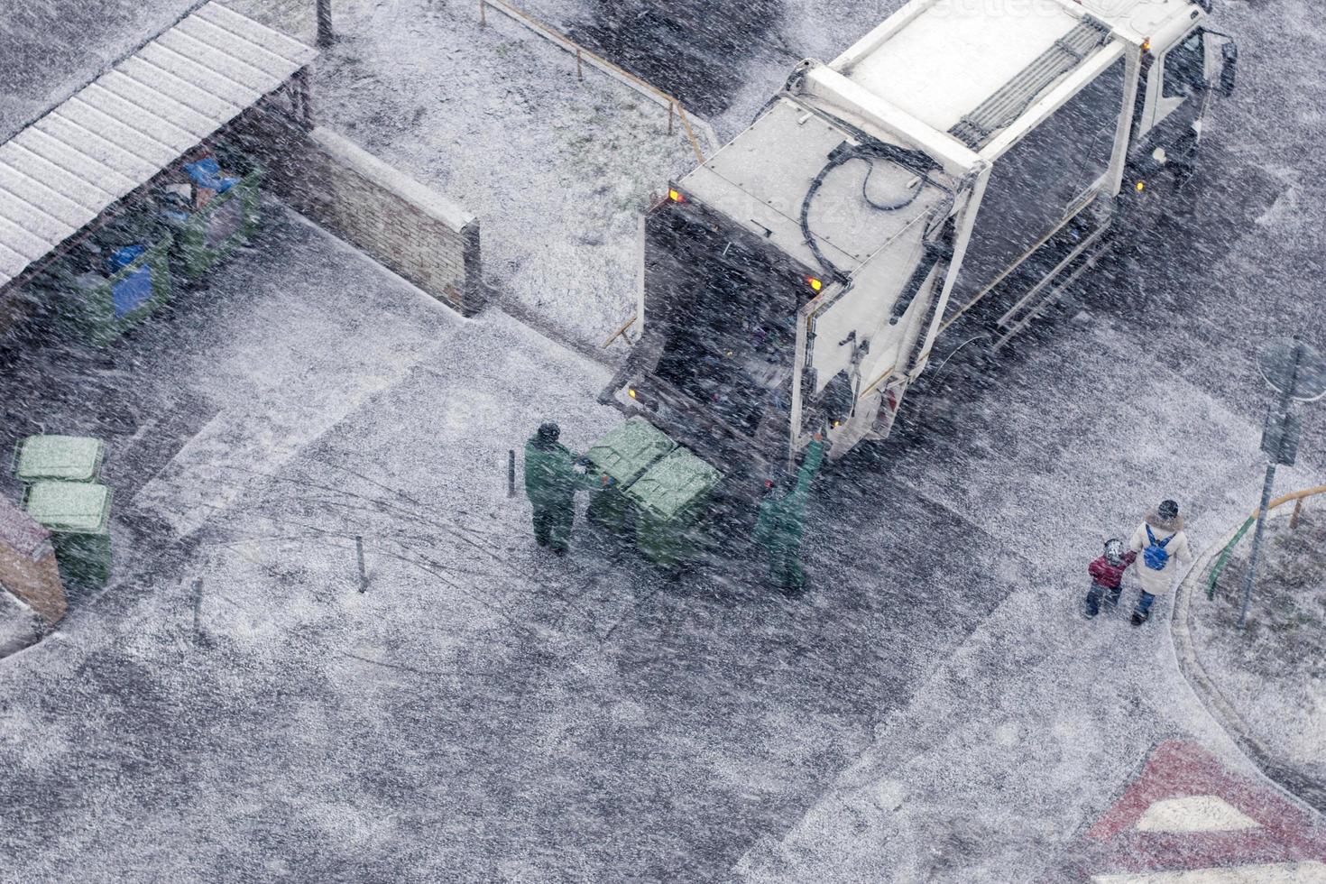 Garbage men in snow storm working in residential area photo