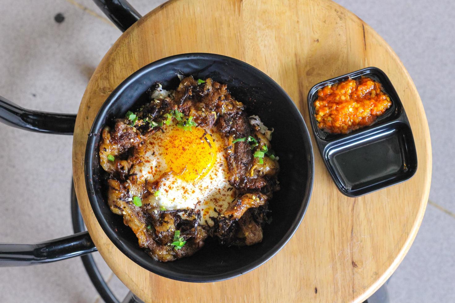 Rice topped with beef and egg on a wooden table in a restaurant photo