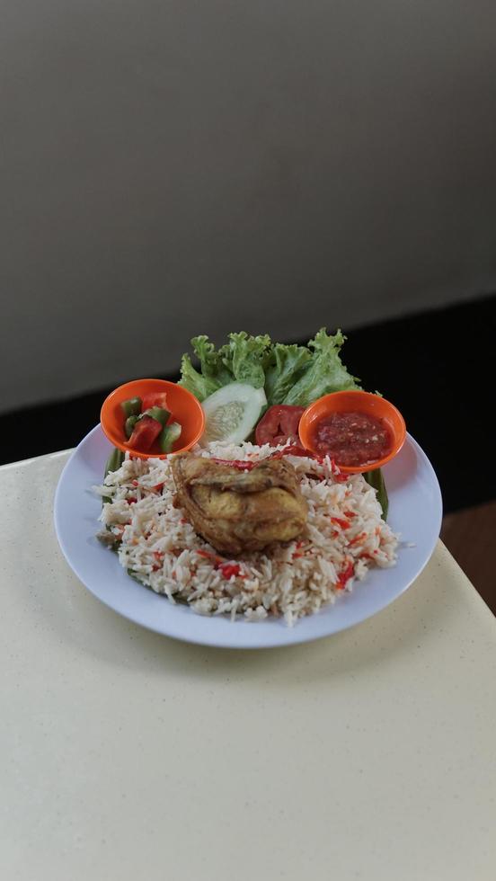 Rice with chicken and vegetables on a white plate in Thai restaurant photo