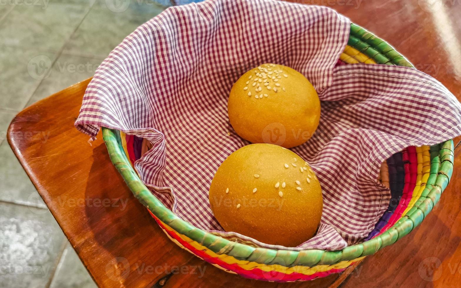 Delicious round buns with sesame seeds on wooden table Mexico. photo