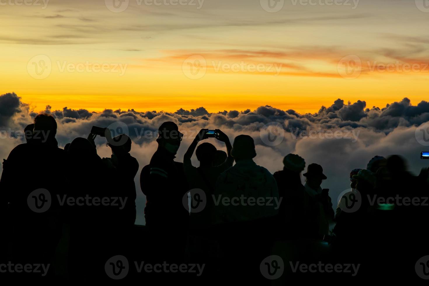 Silhouette person group watching floating sea of clouds,Sea of fog, Sky above clouds,taking cloudscape photos with mobile phones in the morning,sun rising,travel long weekend,Inthanon mountain.