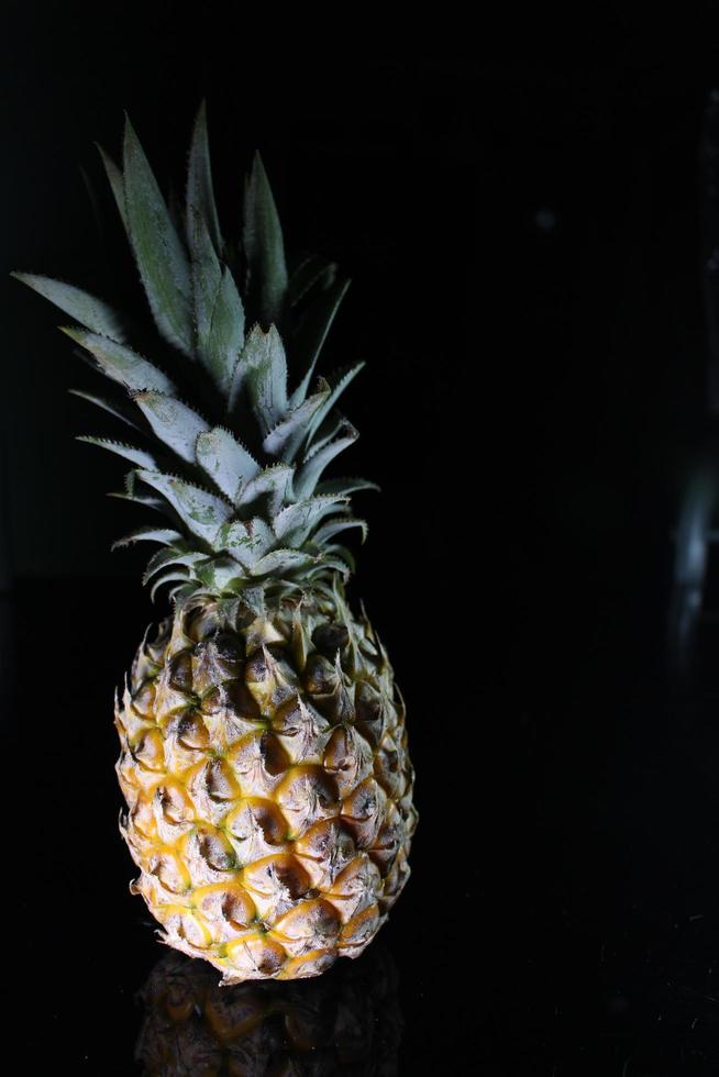 Pineapple fruit isolated on black background with reflection in its shadow. photo