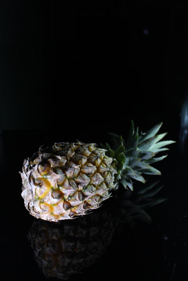 Pineapple fruit isolated on black background with reflection in its shadow. photo