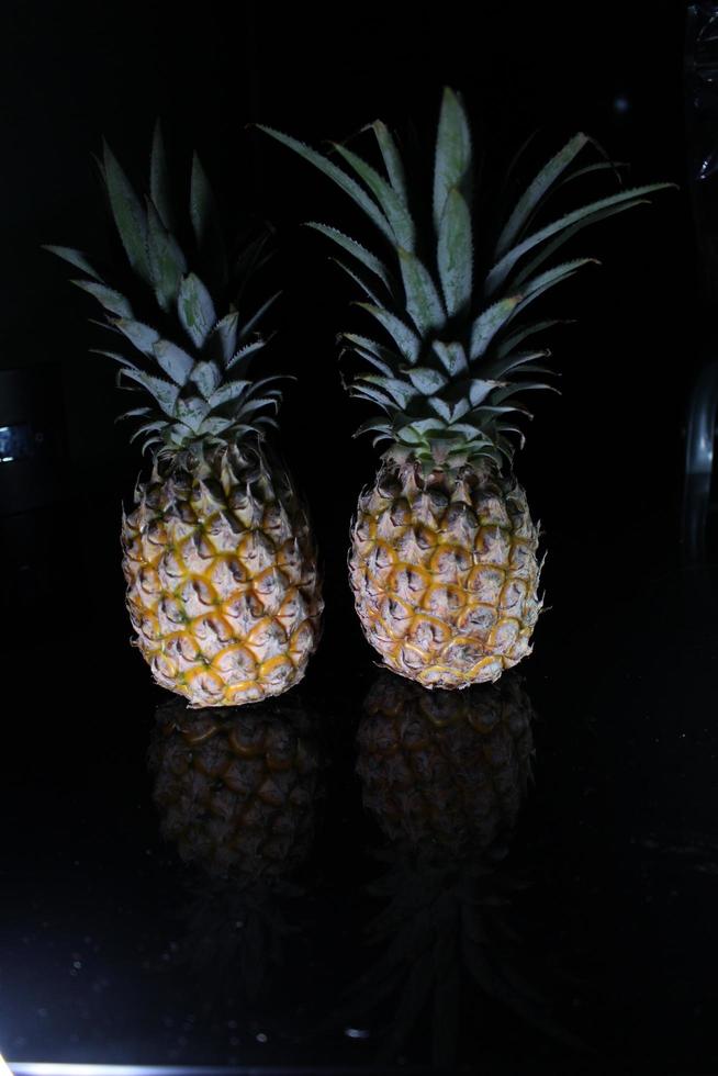 Pineapple fruit isolated on black background with reflection in its shadow. photo