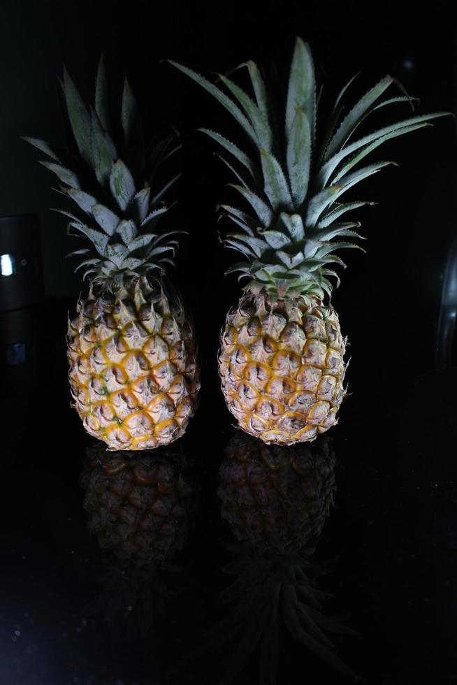 Pineapple fruit isolated on black background with reflection in its shadow. photo