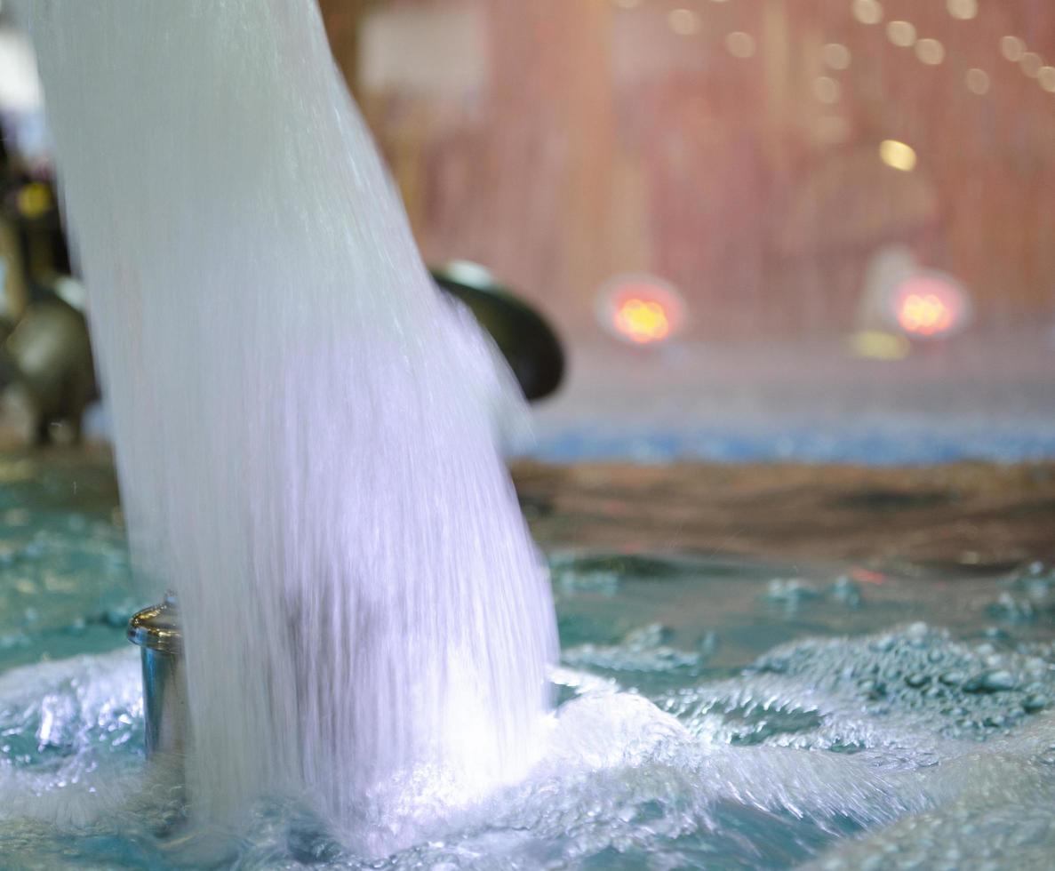 Blurred water background. Backlit water jet in the fountain. photo