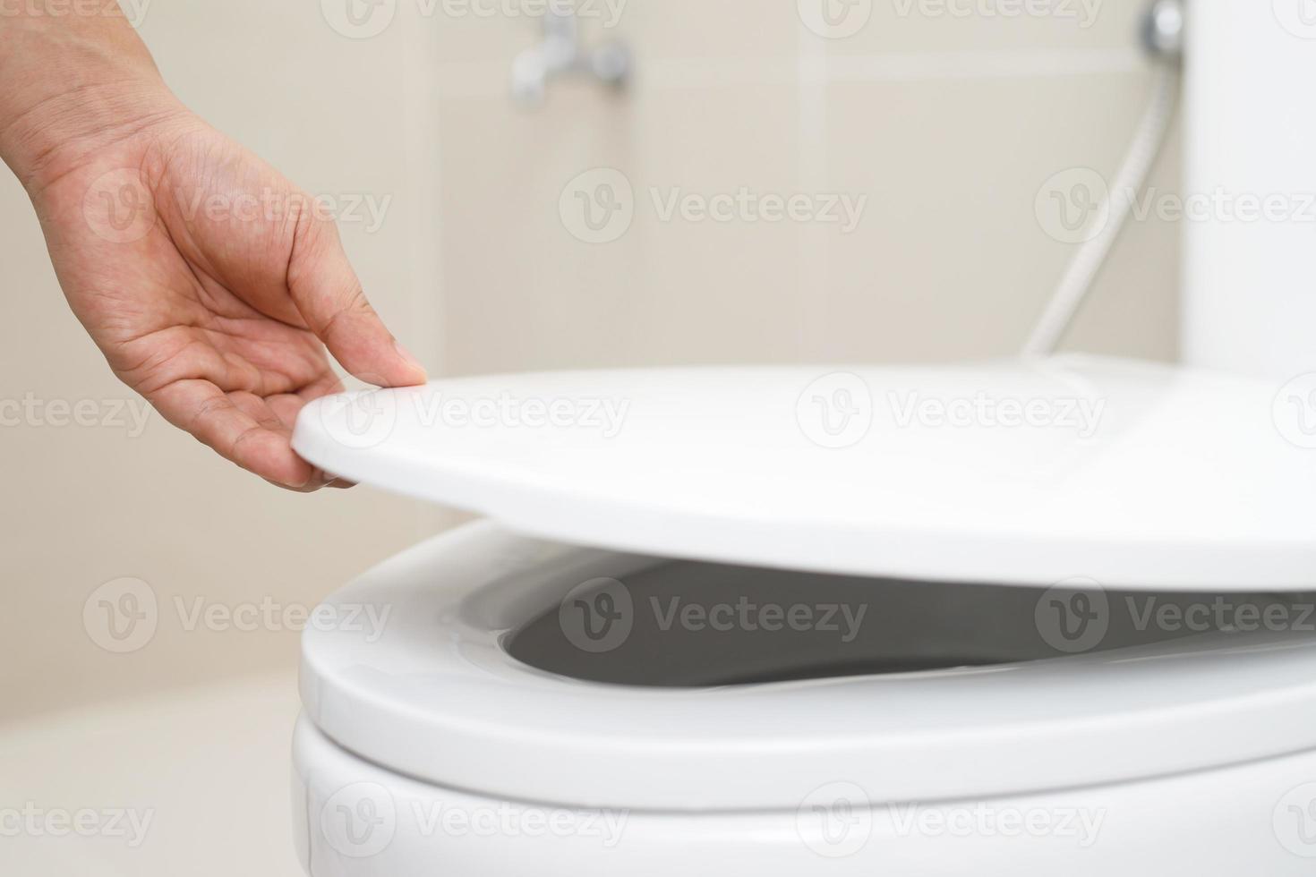 close up hand of a woman closing the lid of a toilet seat. Hygiene and health care concept. photo