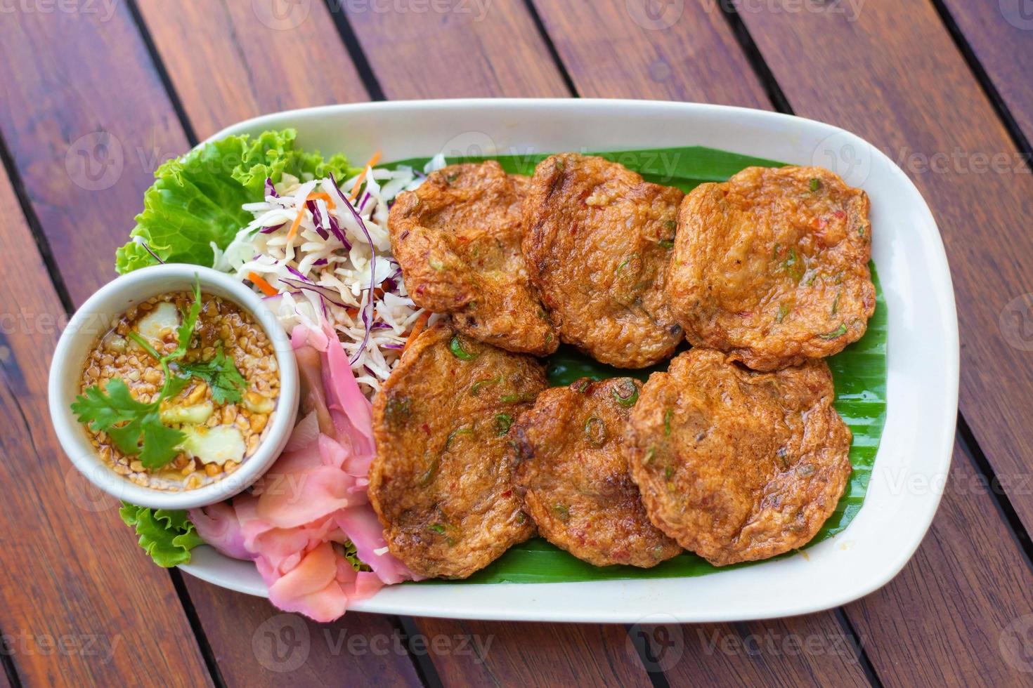 parte superior vista. frito pescado pegar pelotas o profundo frito pescado pastel contiene curry pegar como ingrediente eso es picante tailandés plato servido con inmersión salsa mezclado con Pepino. asiático comida estilo. foto