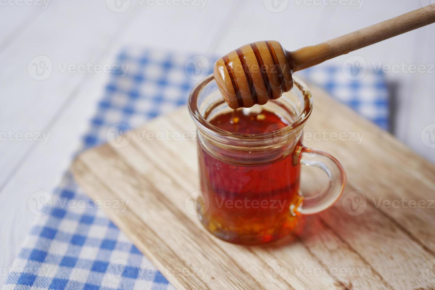 Cerca de miel fresca con una cuchara en la mesa foto