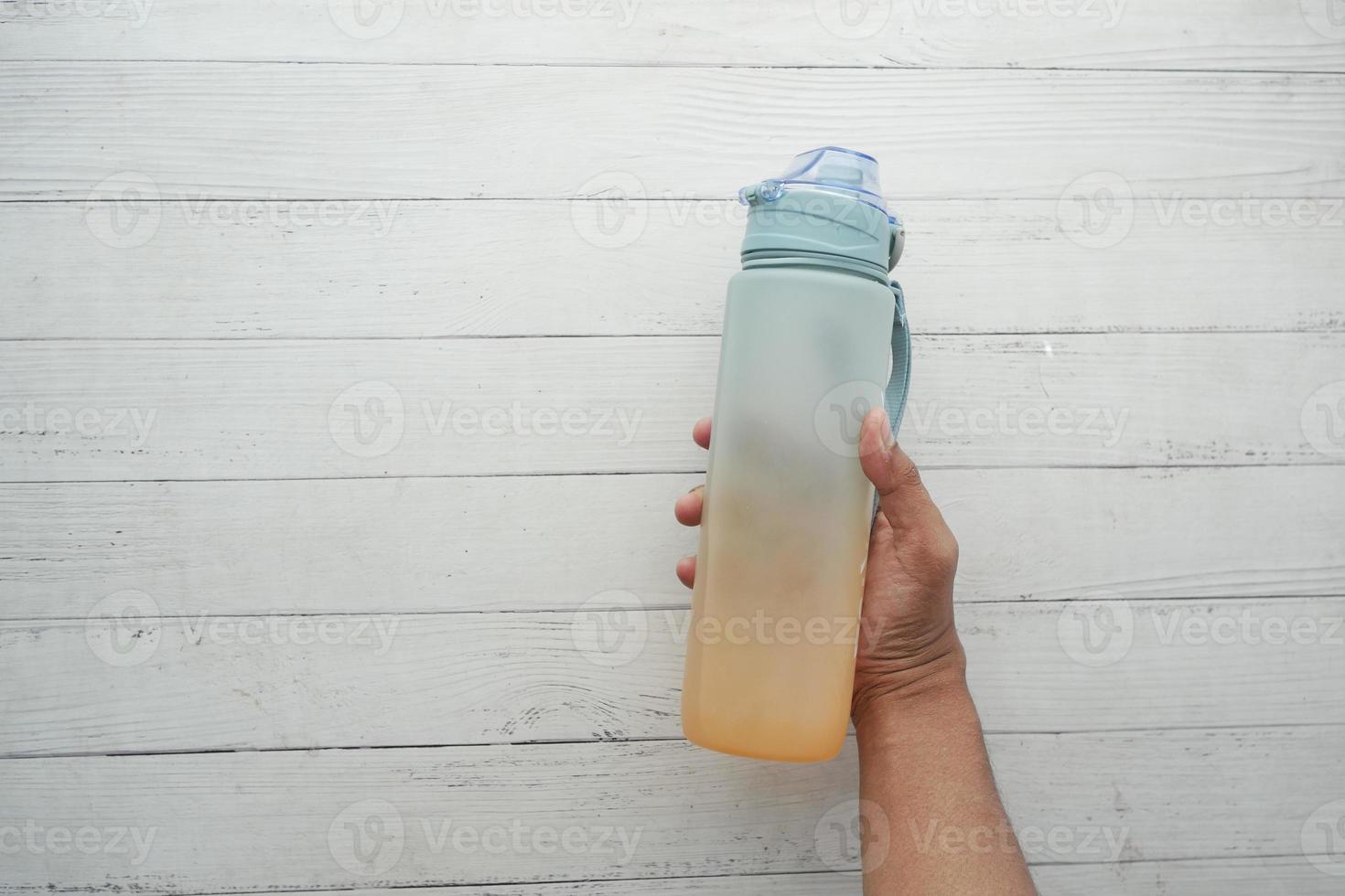 hand holding sport bottle on white wooden table photo