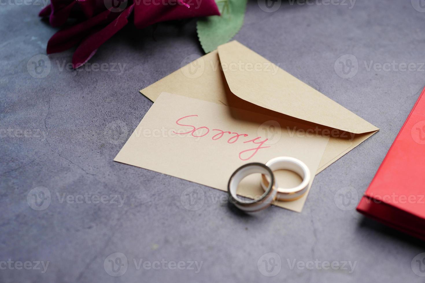 Note with the sorry word next to a wedding ring. photo