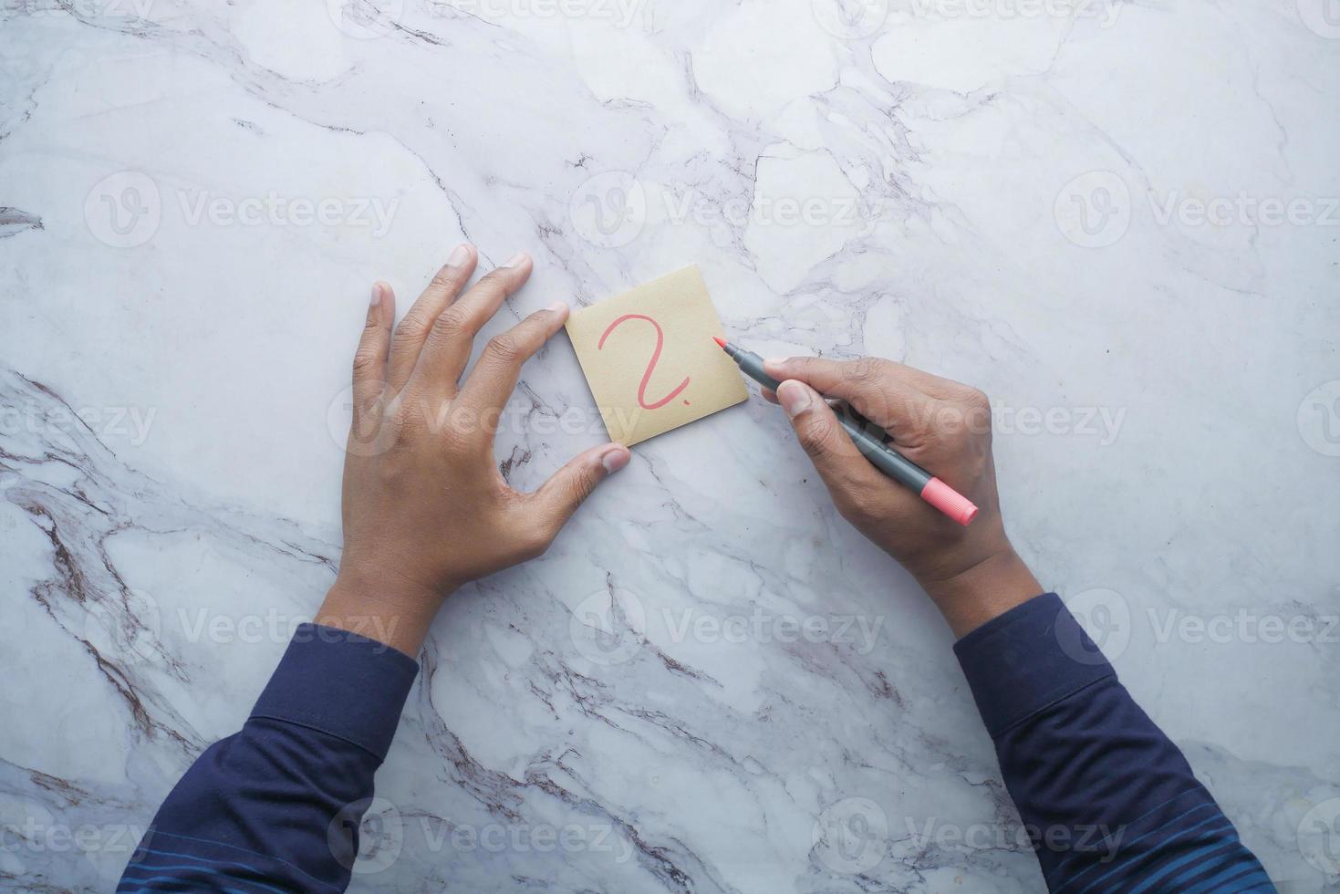 high angle view of hand drawing question mark on paper on office desk photo