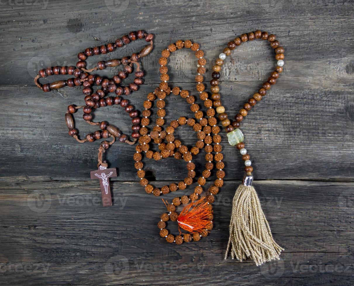 conjunto de rosarios de varios religiones en rústico madera foto