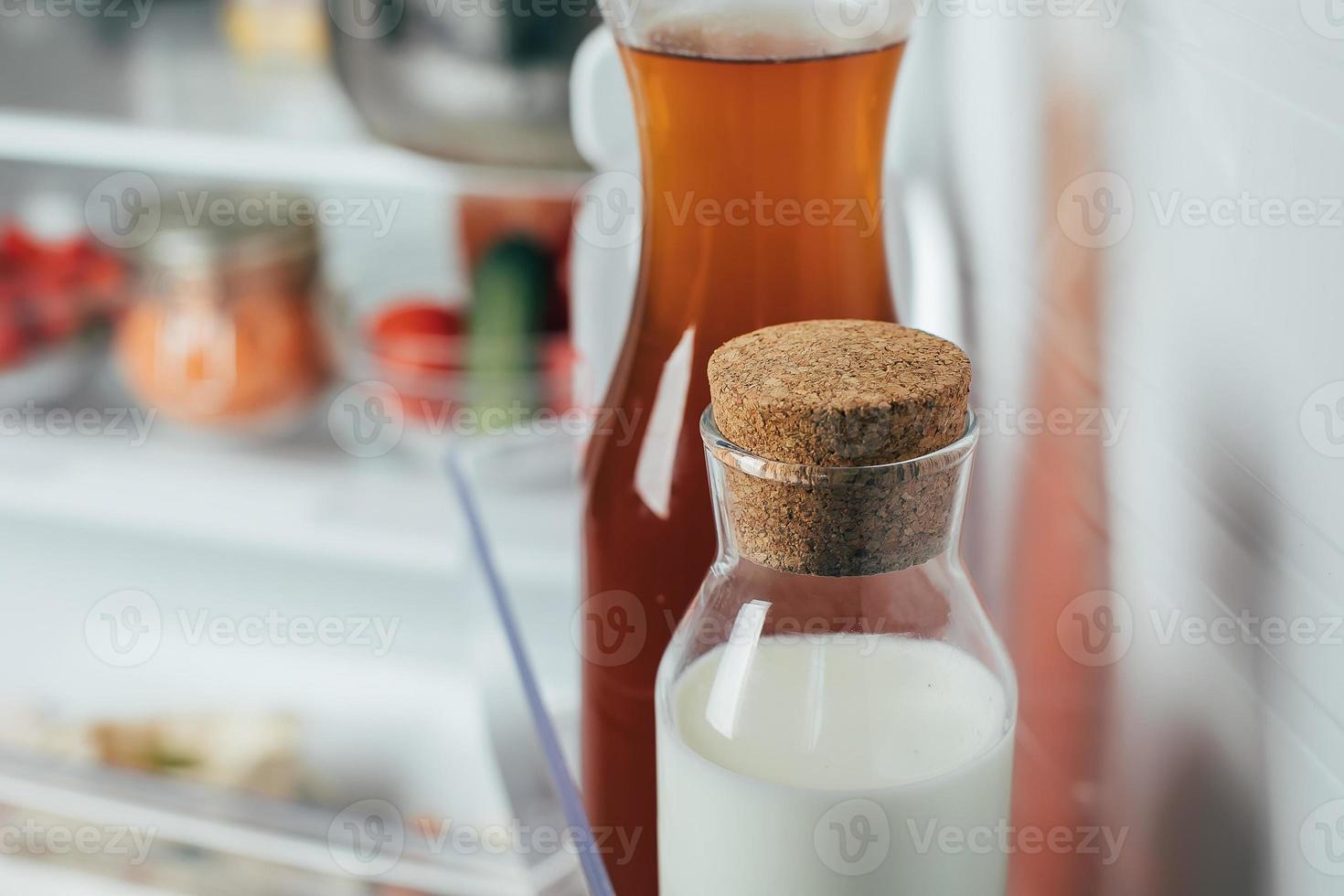 Open Refrigerator Filled with milk bottle, juice bottle and fresh fruits and vegetable. photo