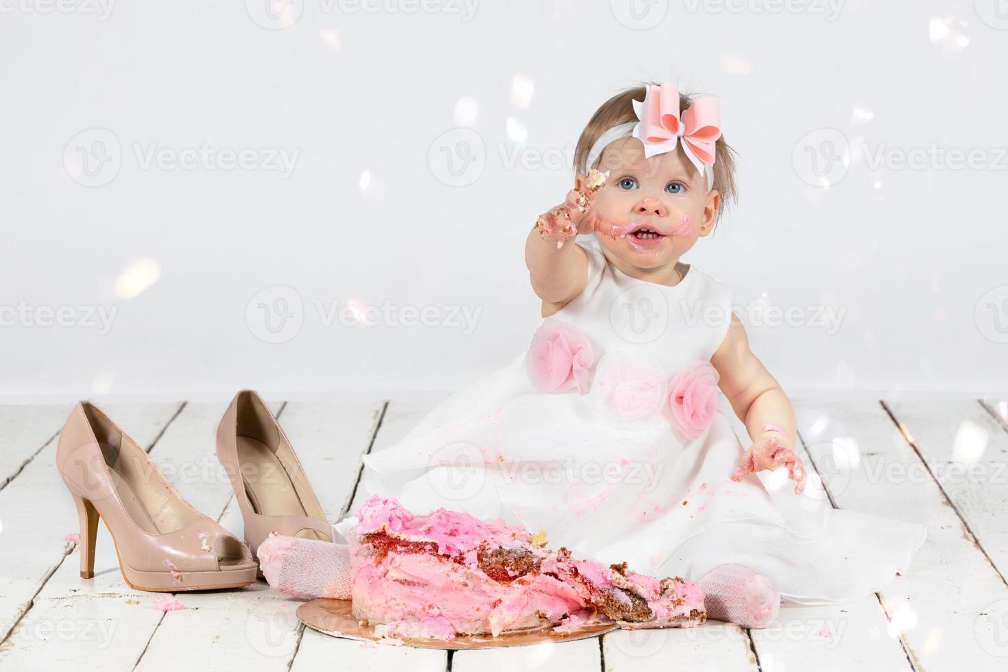 One year old child with a birthday cake. Funny little girl smeared with cream on the first anniversary. Funny child on holiday. photo