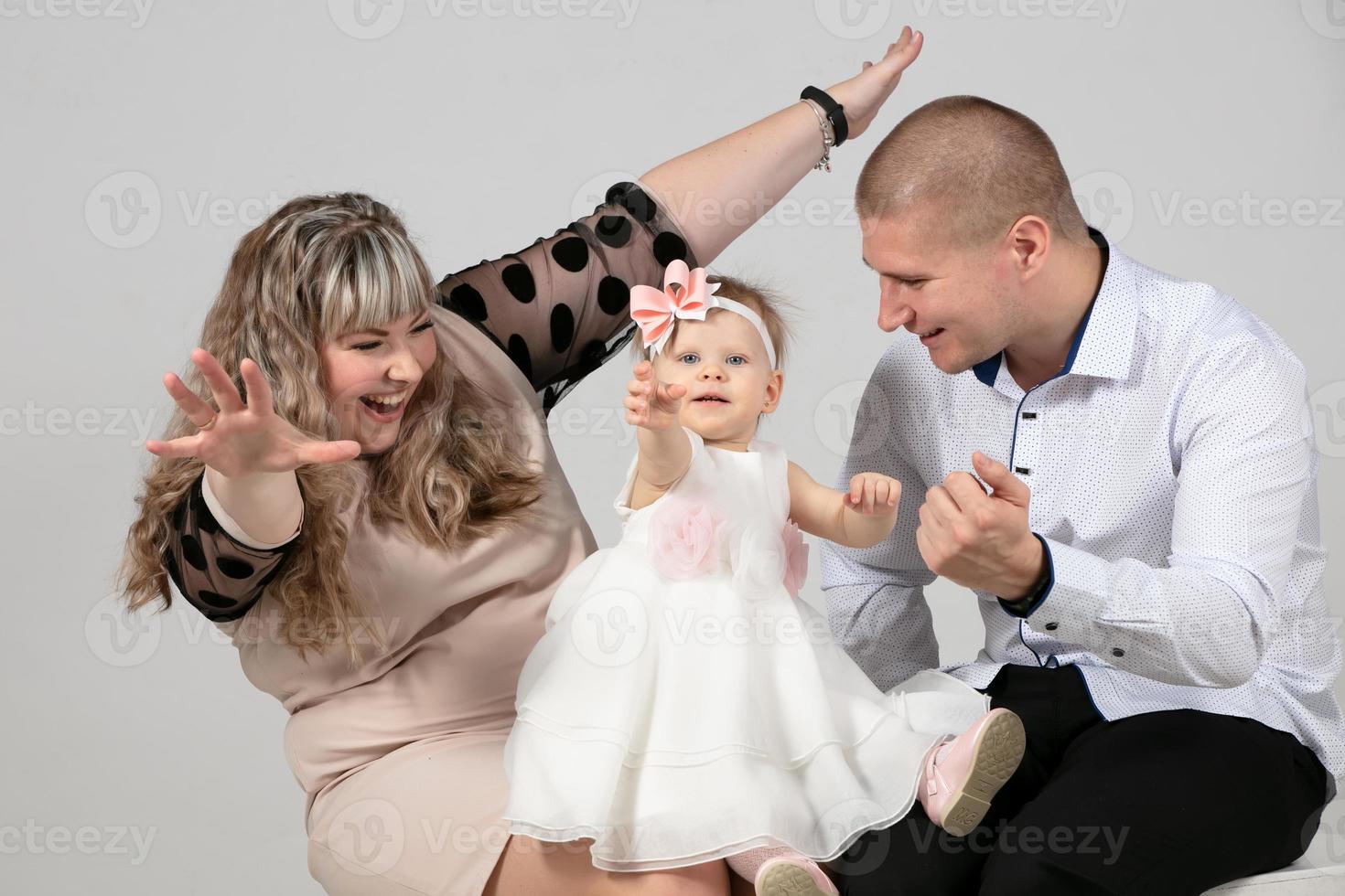 Mom and dad are playing with a little daughter. Beautiful family with baby. One year old child with parents. photo
