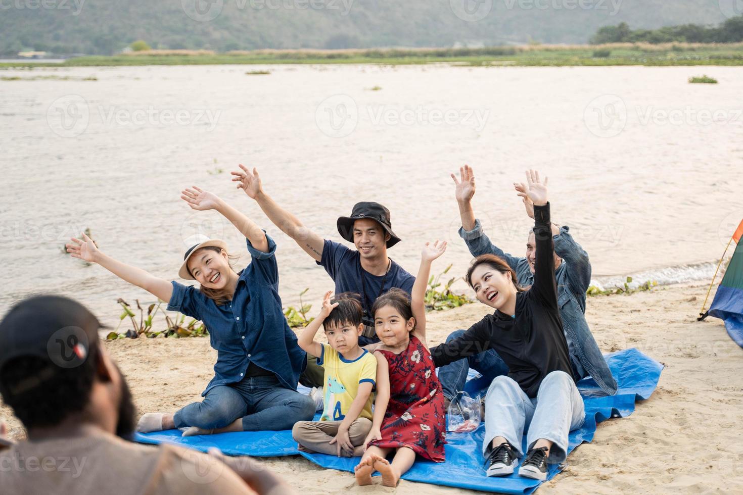 Group of  friends sitting on beach and singing. One man is playing guitar. Summer holidays, vacation, relax and lifestyle concept. Camping time. photo