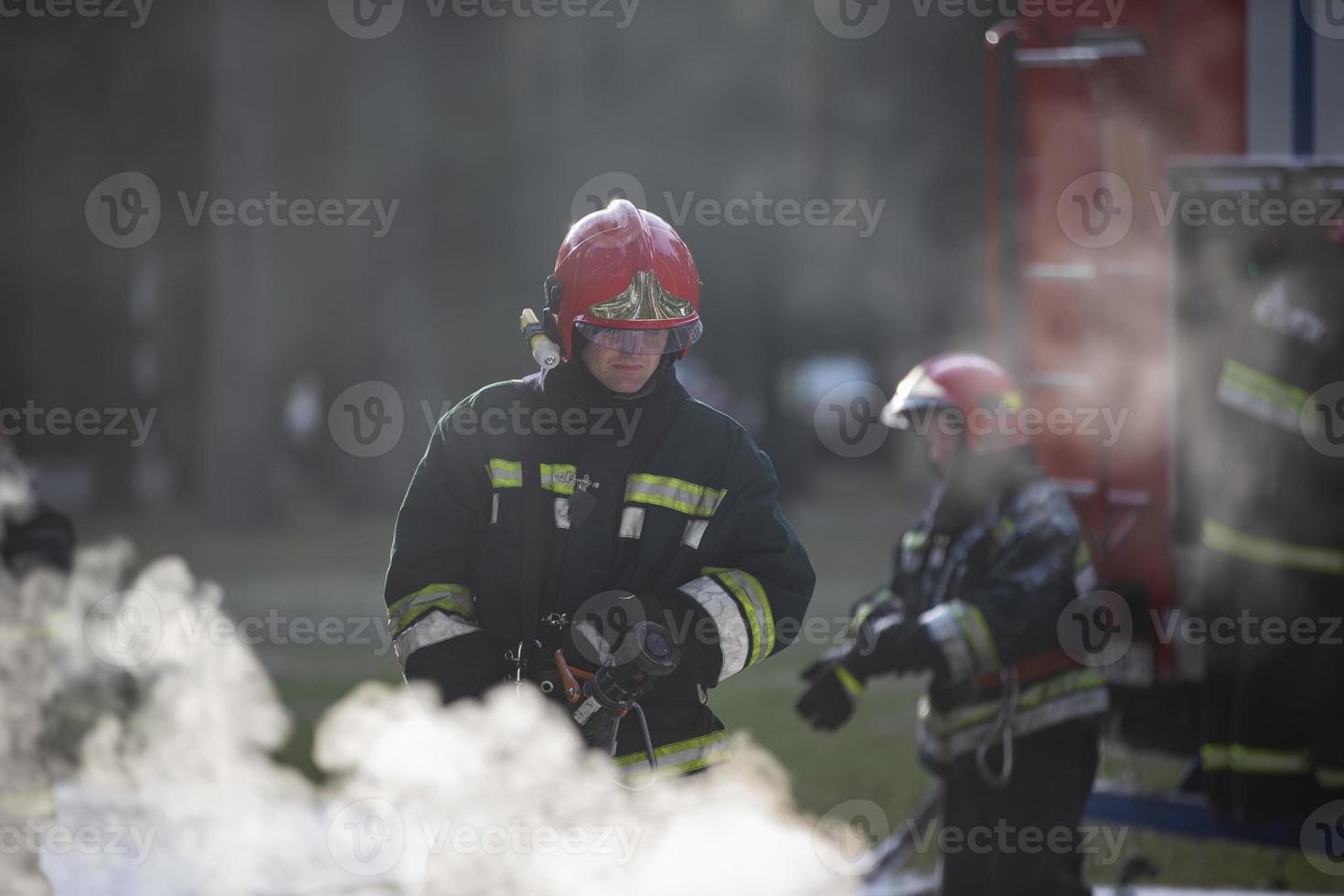 Firefighters extinguish a fire. A team of firefighters on a background of smoke and a fire engine photo