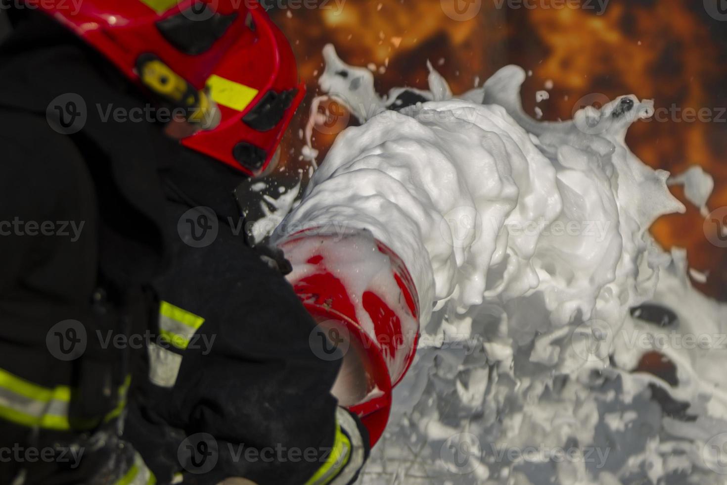 Firefighter puts out a fire. Silhouettes of firefighters with hoses with foam on a background of fire. photo