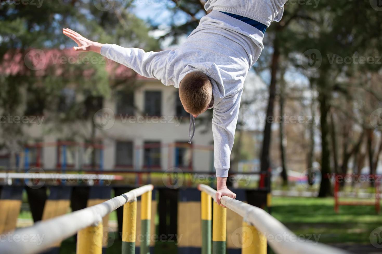 A man does exercises on uneven bars on the street. A man goes in for sports. photo