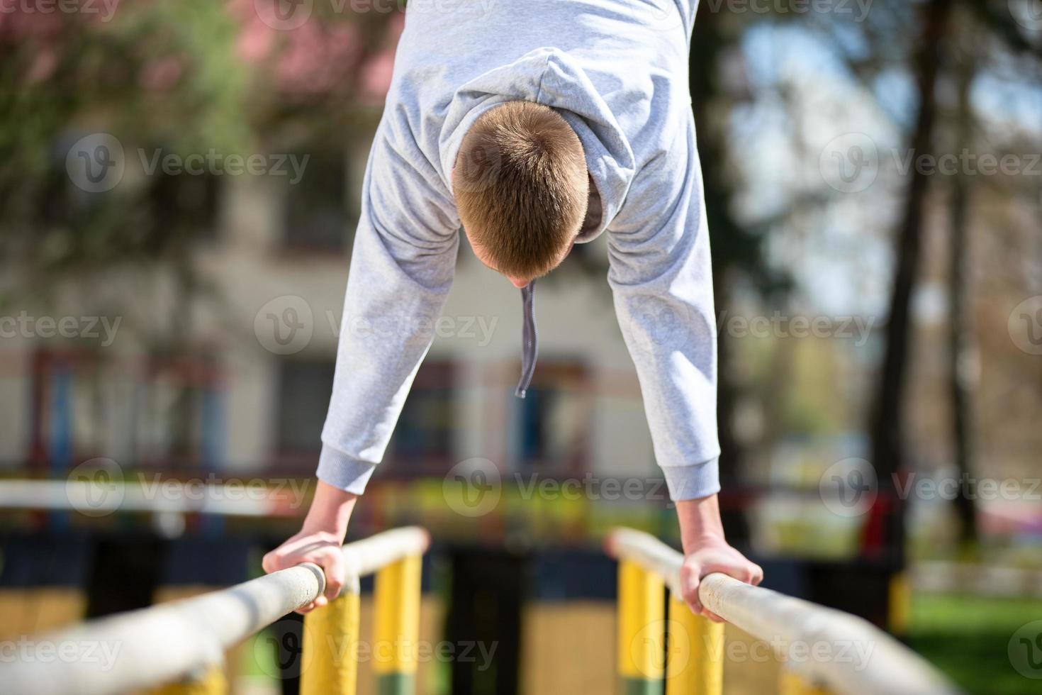 un hombre es comprometido en el desigual barras. hacer ejercicios en el calle. foto