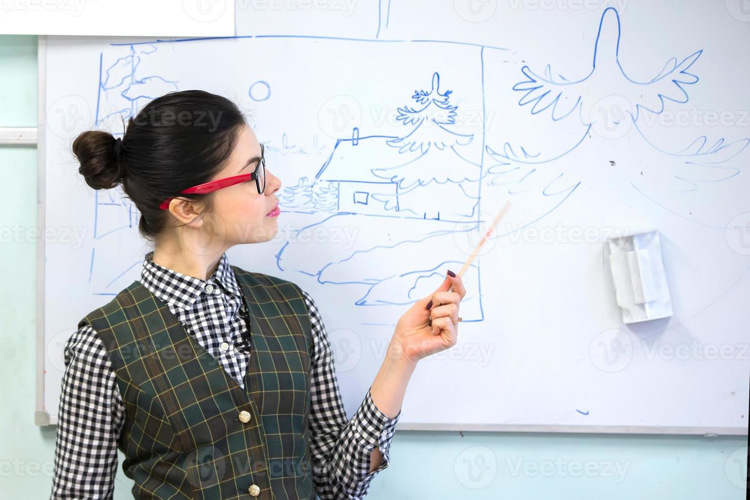 Teacher with a pointer near the blackboard. Teacher of drawing. photo
