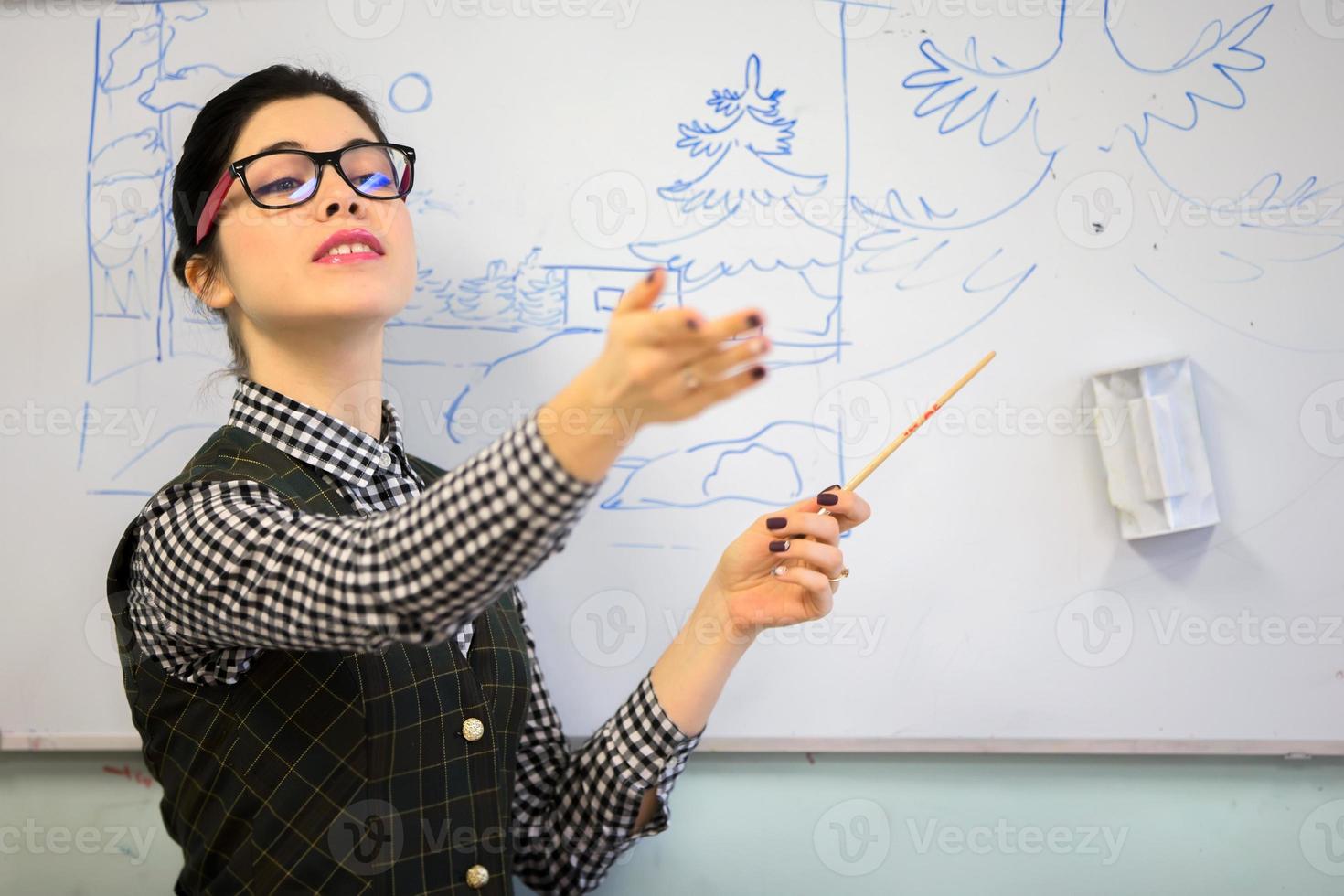 Teacher with a pointer near the blackboard. Teacher of drawing. photo