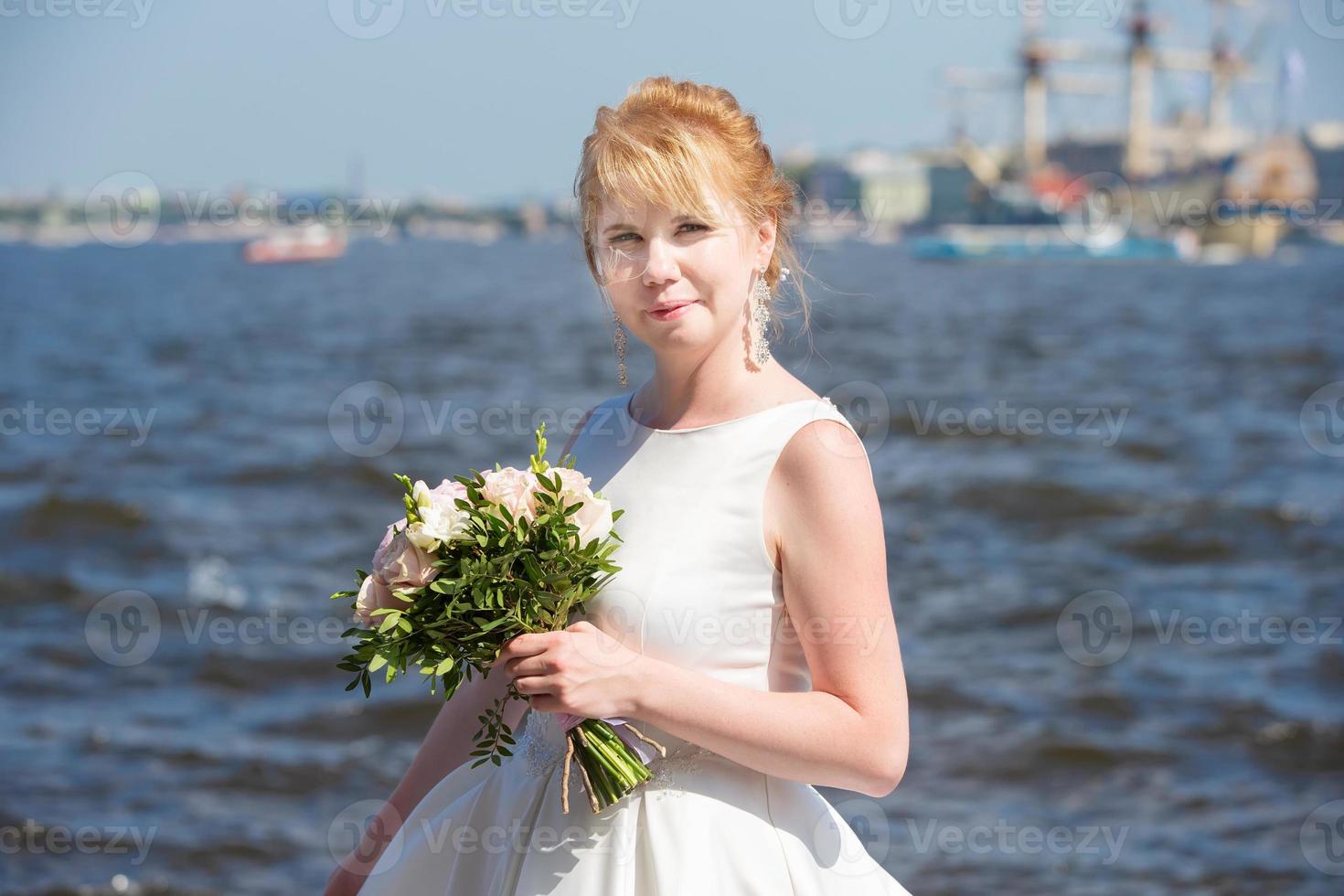 Bride with a bouquet on the background of the river. photo