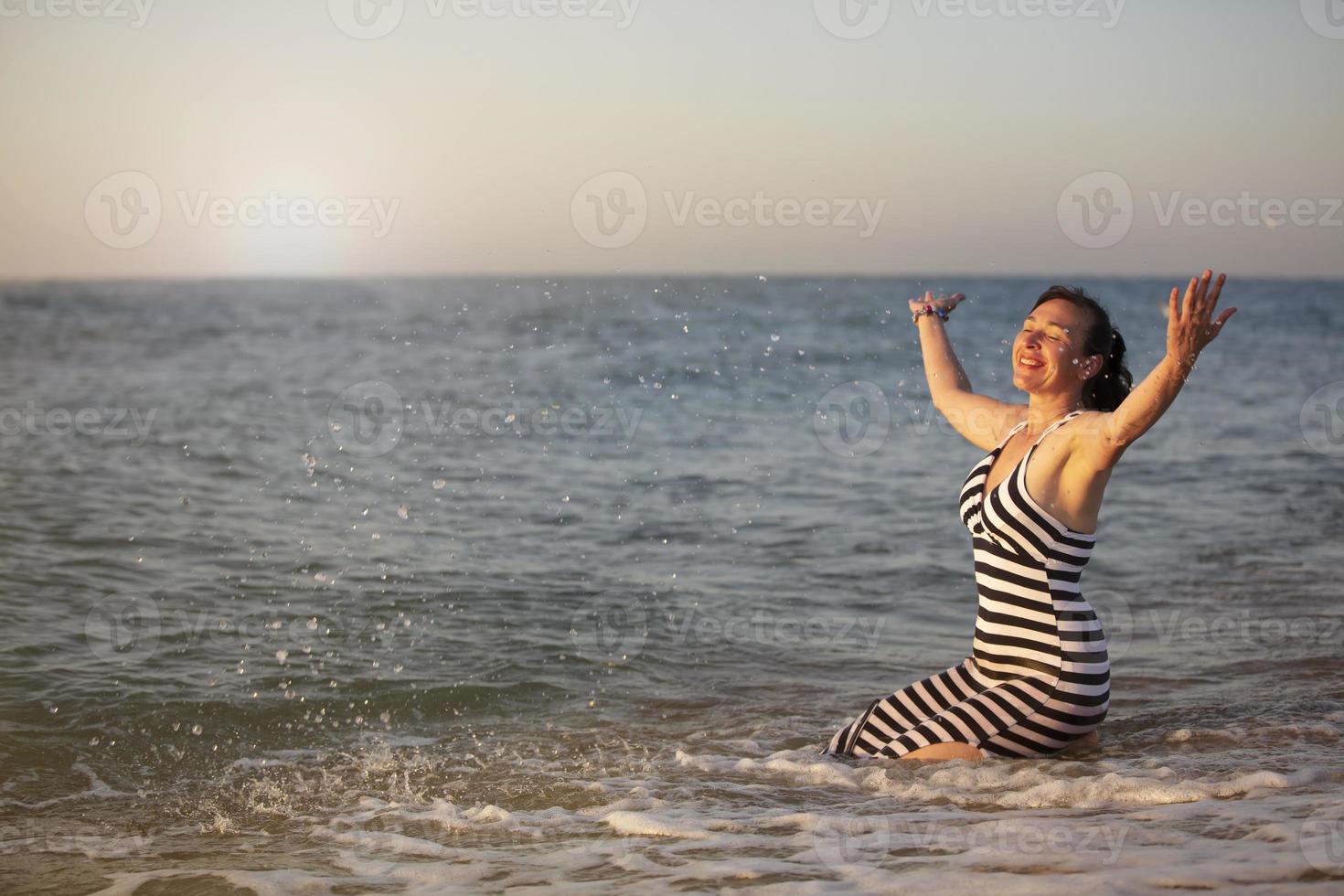 Rest at the resort. An elderly woman on vacation by the sea spread her arms. photo