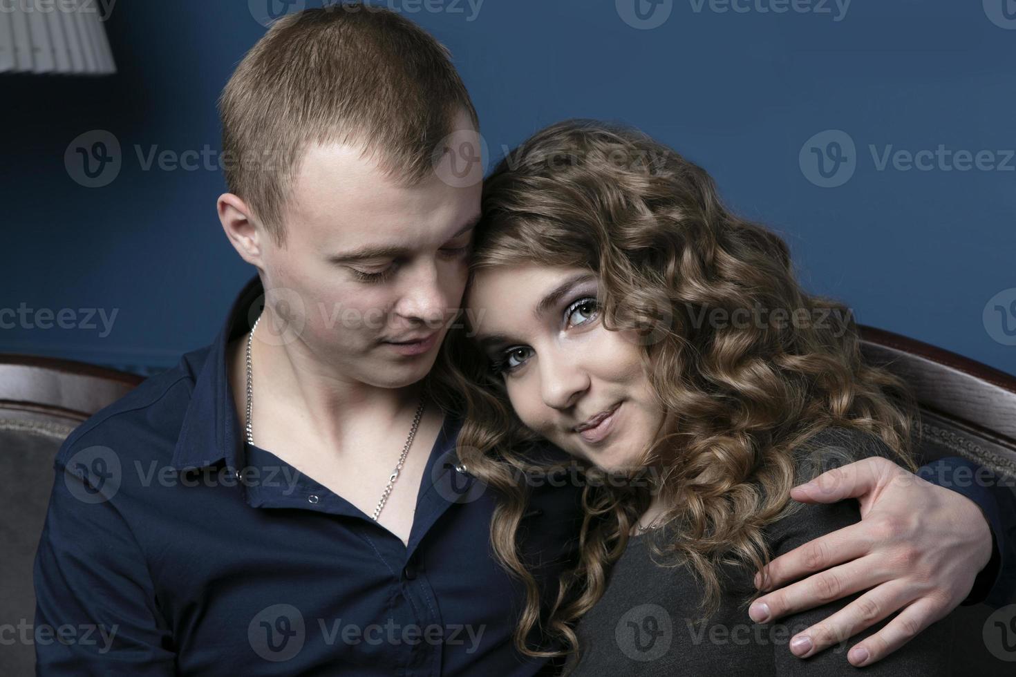 The guy and the girl are sitting embracing. A young couple. Lovers. A man takes on a beautiful woman. photo