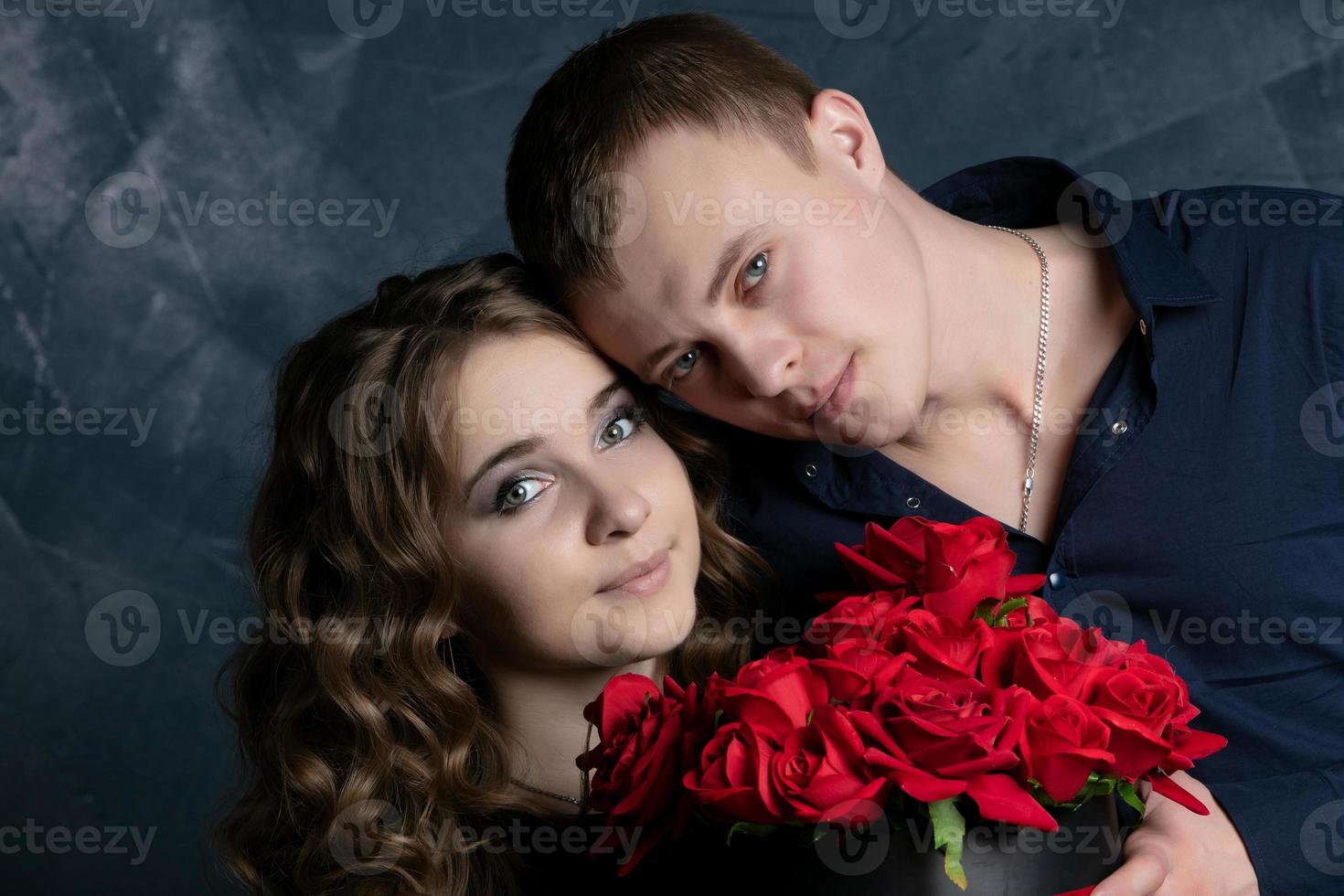 retrato de un hermosa Pareja en amor en un oscuro antecedentes. caras de un niña y un chico de cerca con rosas. San Valentín día. foto