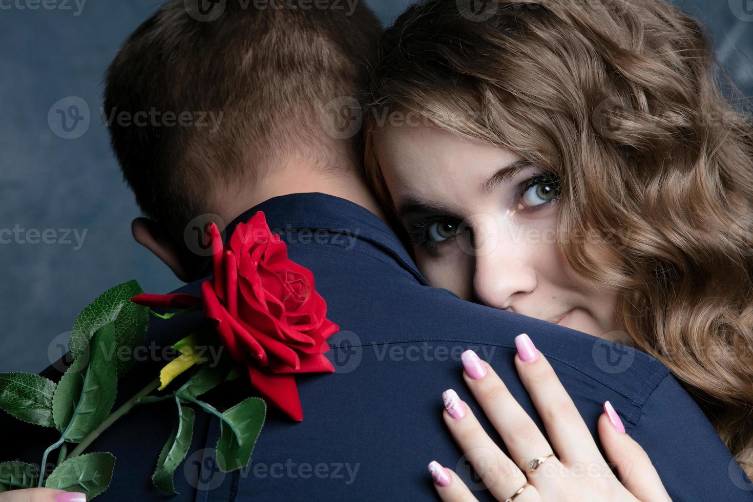 The face of a beautiful girl with a red rose on the shoulder of a guy. Valentine's Day. Lovers. Romantic date. photo