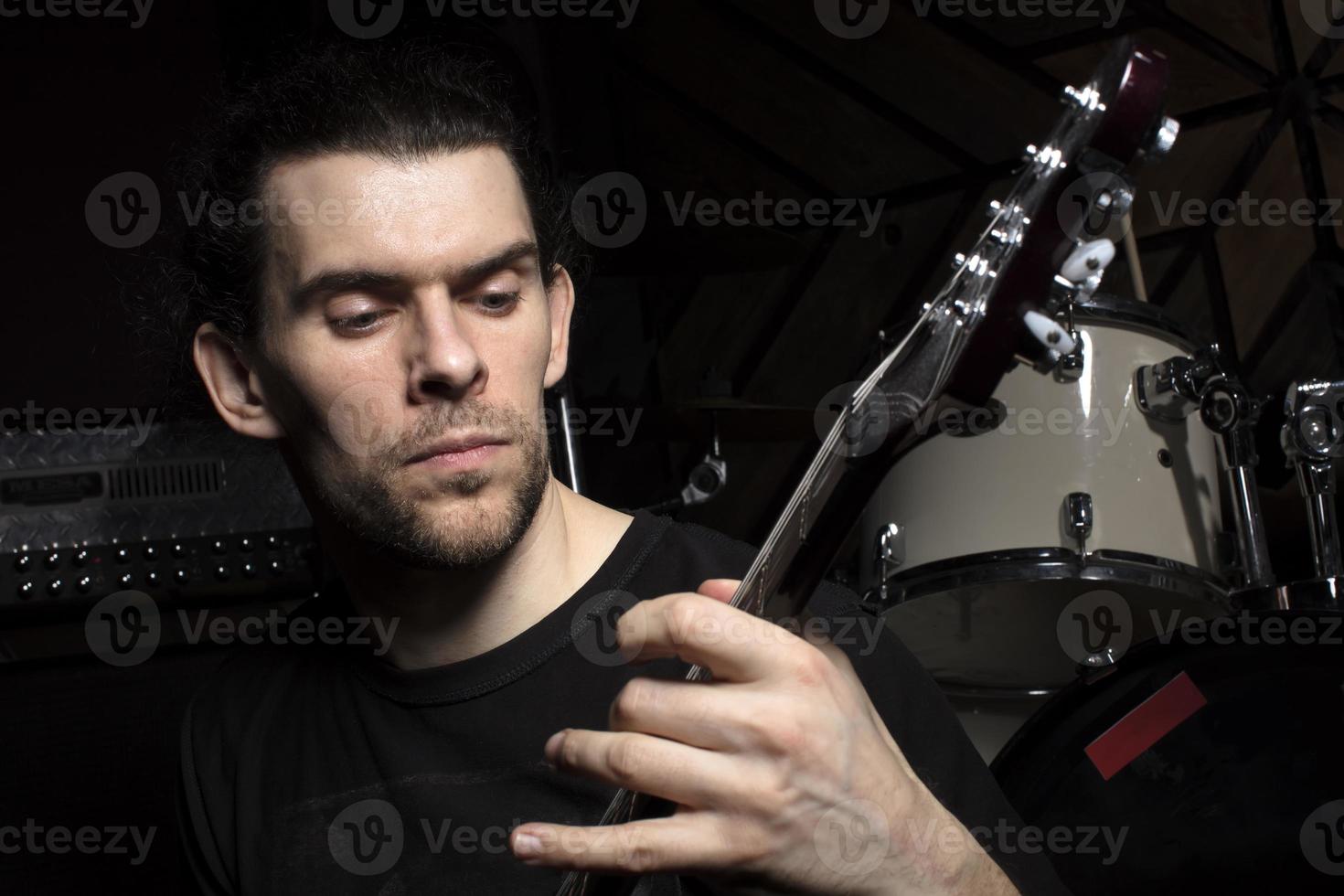 A man plays the guitar. Face of a man with a musical instrument on a dark background. photo