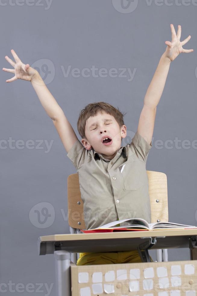 The child yawns in the classroom. Elementary school student wants to sleep in class. photo