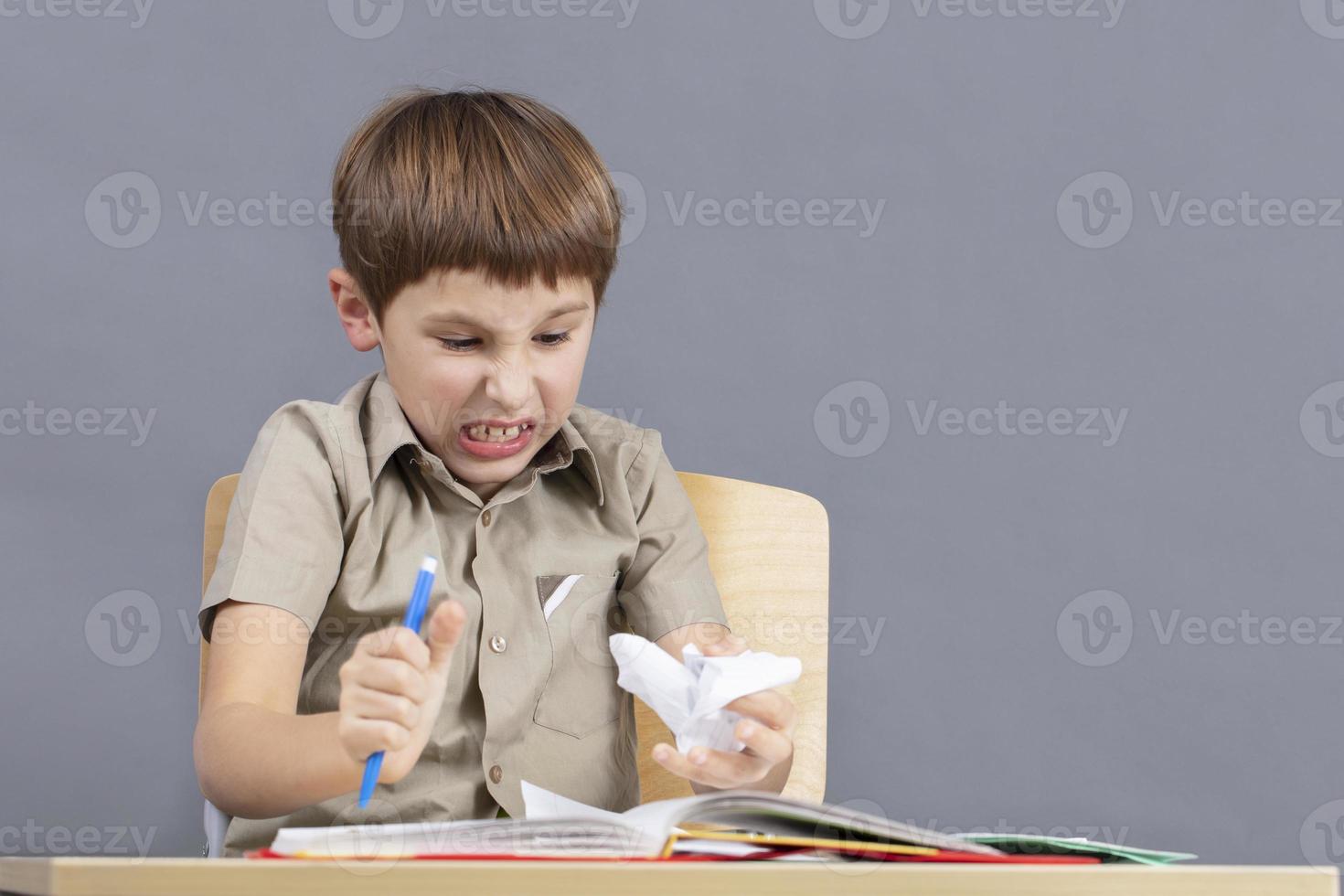 The child is angry at homework. An elementary school student is tearing paper. photo