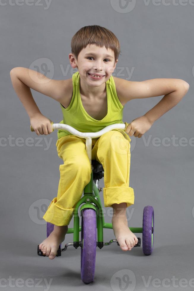 Upright, a child in bright clothes barefoot rides a children's bicycle. photo