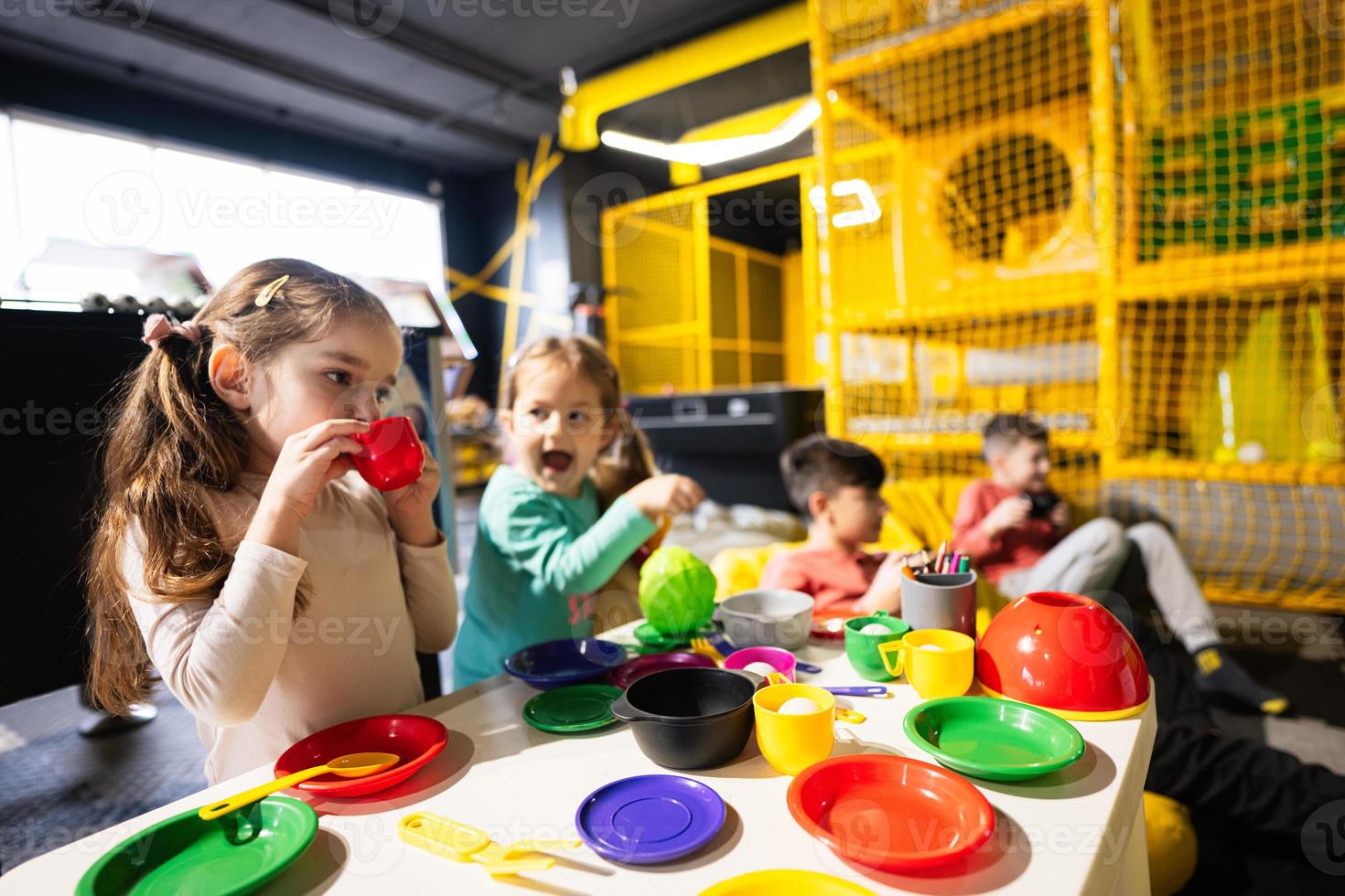 Two sisrers playing in kids kitchen at children play center. photo