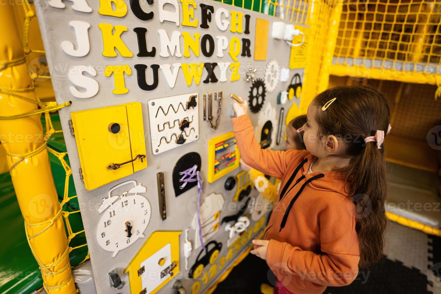 Two sisters playing with busy board at kids play center. photo