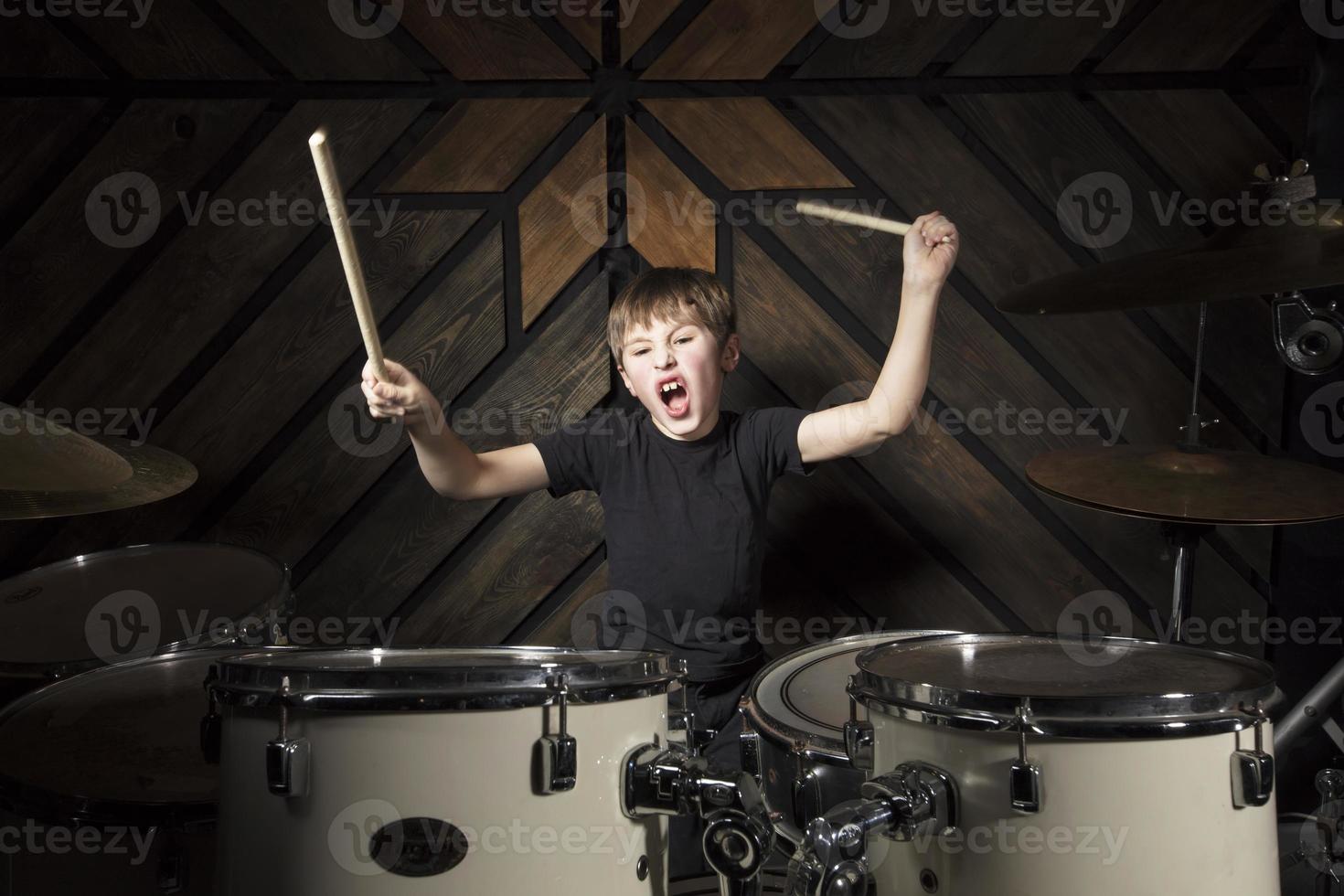 The child plays the drums. Boy musician behind a drum kit. photo