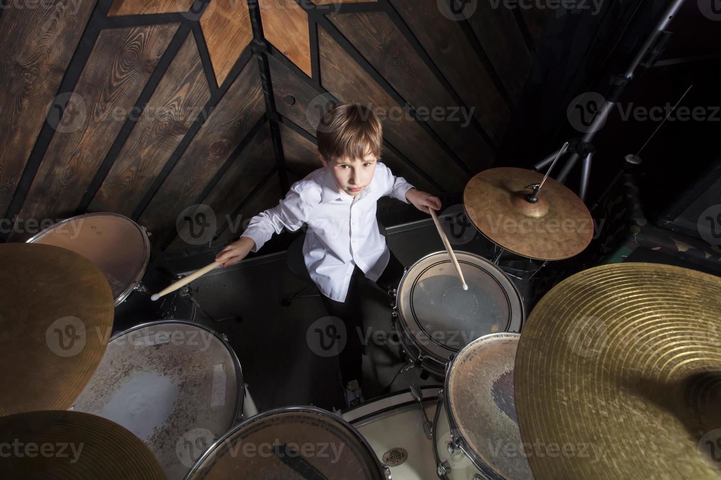 The boy learns to play the drums. The child behind the drum kit. photo