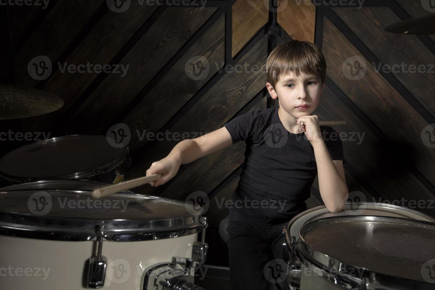 The child plays the drums. Boy musician behind a drum kit. photo