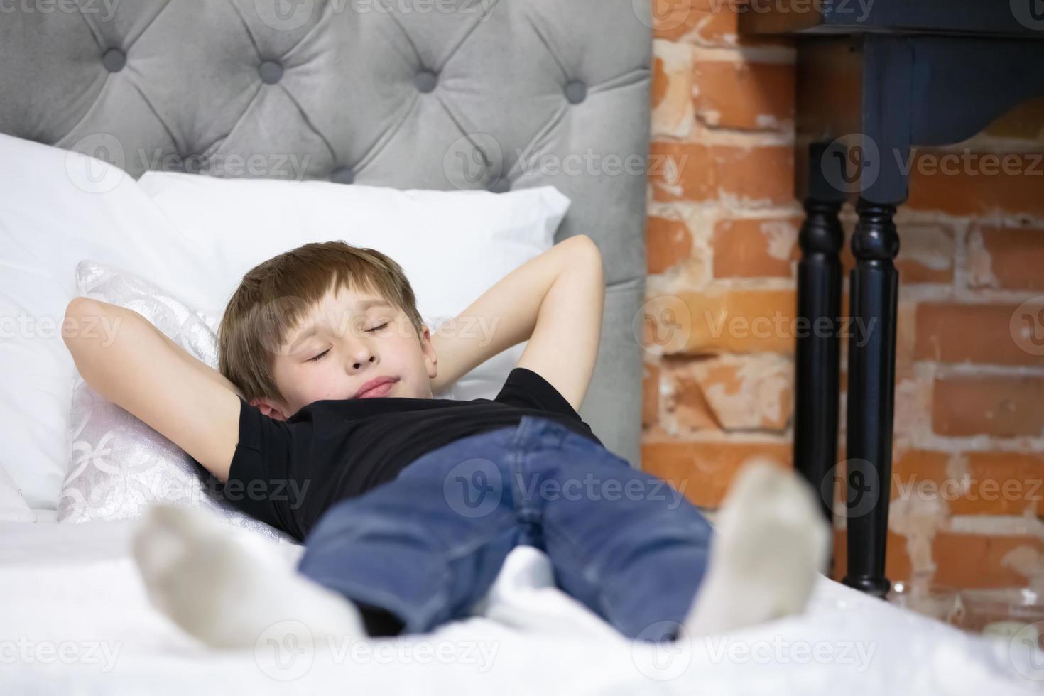 el niño duerme acostado en el cama. el edad escolar chico cayó dormido. foto