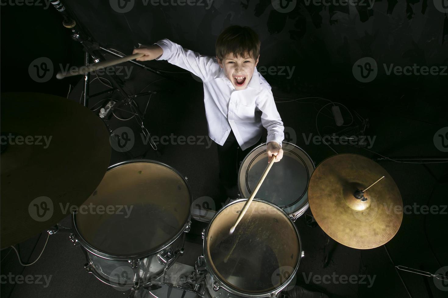 The child plays the drums. Boy musician behind a drum kit. photo