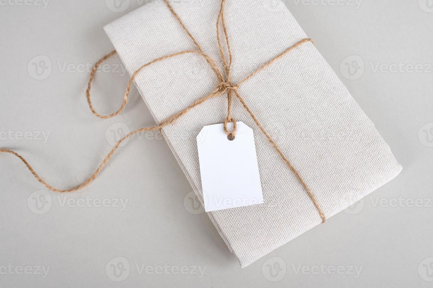 Tag mockup on folded cotton fabric, new beige clothes with blank clothes tag on white background photo